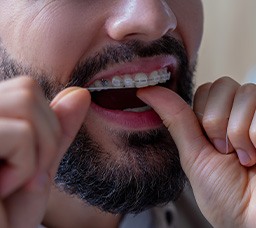 Man wearing braces and flossing his teeth