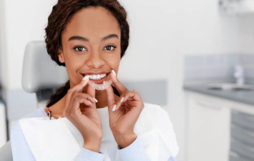 Woman in dentist’s chair inserting aligner