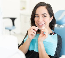 Woman in dentist’s chair holding Invisalign