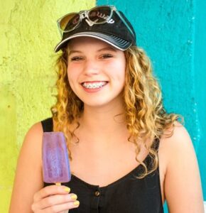 Young woman with braces eating a popsicle 